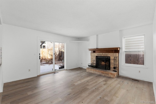 unfurnished living room featuring light hardwood / wood-style floors and a brick fireplace