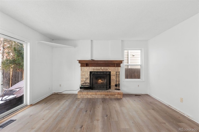 unfurnished living room featuring a textured ceiling, light wood-type flooring, and a healthy amount of sunlight