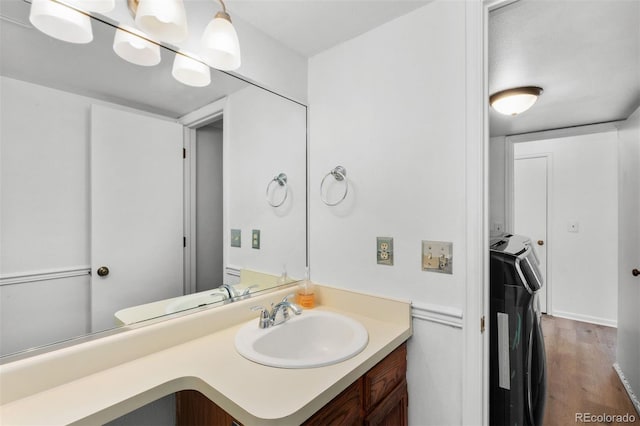 bathroom featuring washing machine and clothes dryer, vanity, and hardwood / wood-style flooring