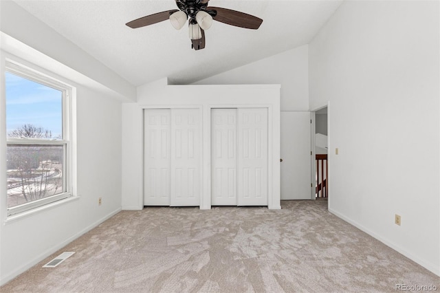 unfurnished bedroom with multiple closets, ceiling fan, light carpet, and vaulted ceiling