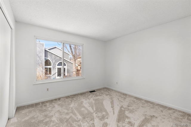 spare room with light colored carpet and a textured ceiling