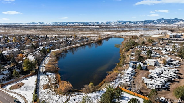 snowy aerial view featuring a water and mountain view