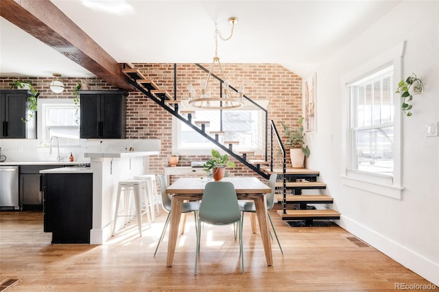 4452 Stuart St, Denver, CO 80212 - dining space with stairway, brick wall, light wood-style flooring, and baseboards