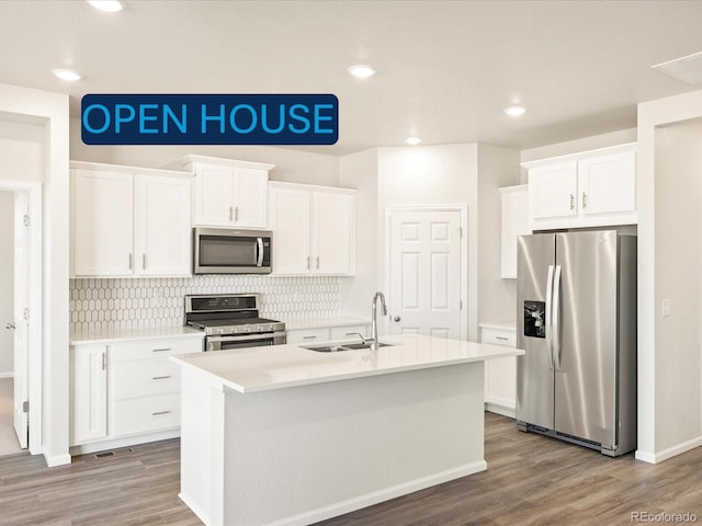 kitchen featuring appliances with stainless steel finishes, sink, a center island with sink, and white cabinets