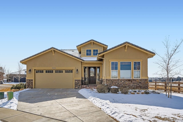 view of front of property featuring stucco siding, fence, a garage, stone siding, and driveway