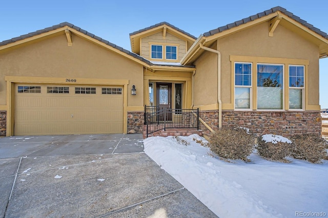 view of front of property featuring an attached garage, stone siding, driveway, and stucco siding