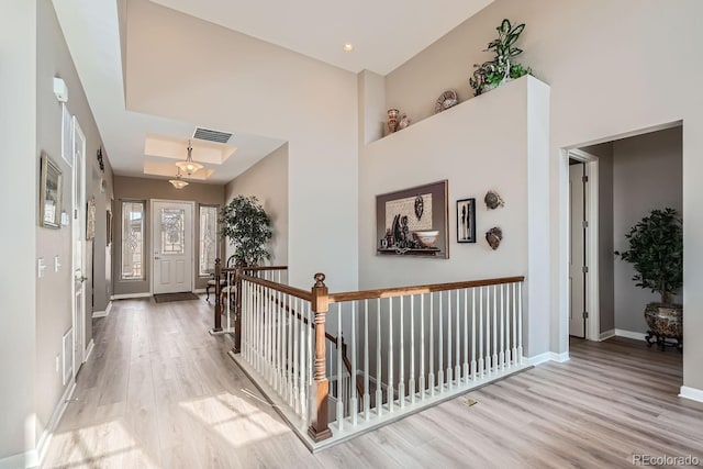 entryway featuring light wood-type flooring, baseboards, a high ceiling, and visible vents