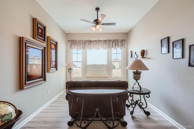 living area featuring ceiling fan, light wood-style flooring, and baseboards