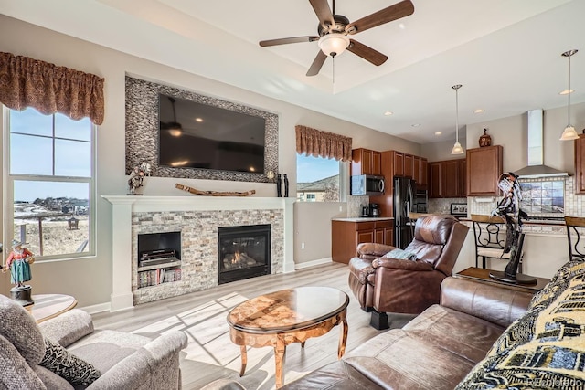 living room with baseboards, a ceiling fan, light wood-style floors, a fireplace, and recessed lighting