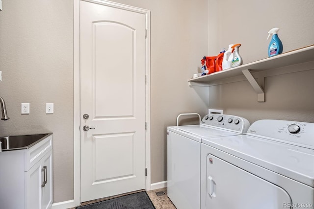 washroom featuring cabinet space, washing machine and dryer, baseboards, and a sink