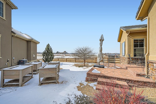 yard layered in snow featuring a patio area, central AC, and fence