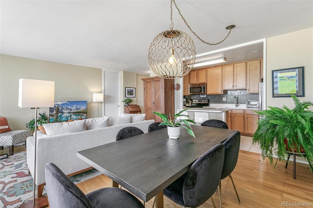 dining room with sink, an inviting chandelier, and light wood-type flooring