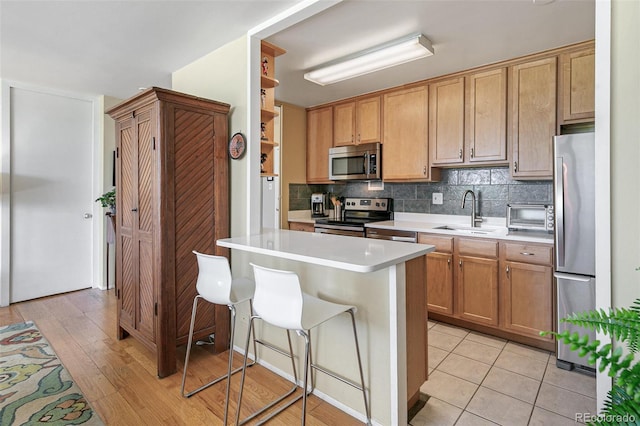 kitchen with a kitchen island, appliances with stainless steel finishes, sink, a breakfast bar area, and decorative backsplash