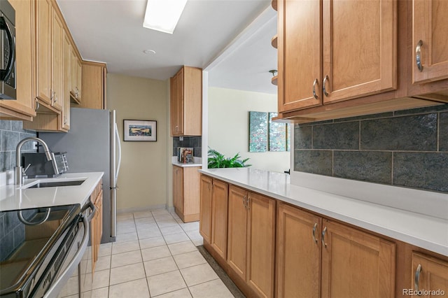 kitchen with stove, light tile patterned floors, backsplash, and sink