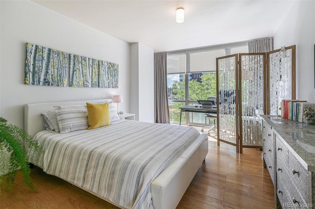 bedroom with expansive windows and dark hardwood / wood-style floors