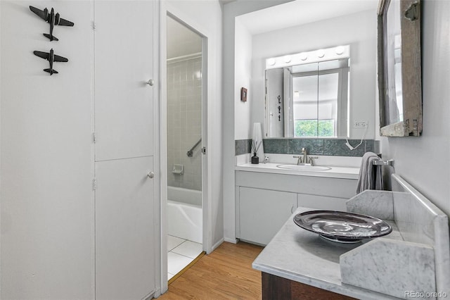 bathroom with vanity, tiled shower / bath combo, and wood-type flooring