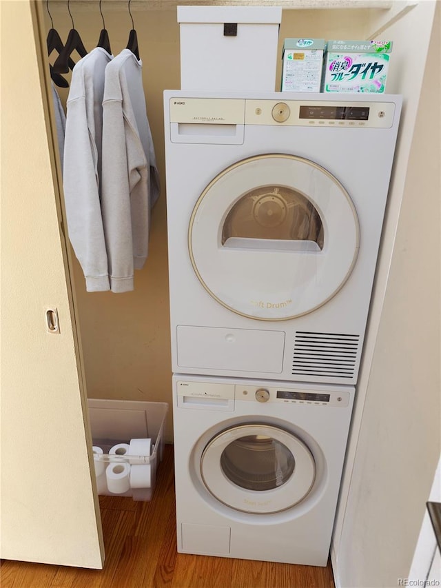 clothes washing area with hardwood / wood-style flooring and stacked washing maching and dryer