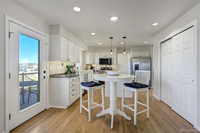 1944 Queens Canyon Ct, Colorado Springs, CO 80921 - kitchen with stainless steel appliances, light wood finished floors, white cabinetry, and a breakfast bar area