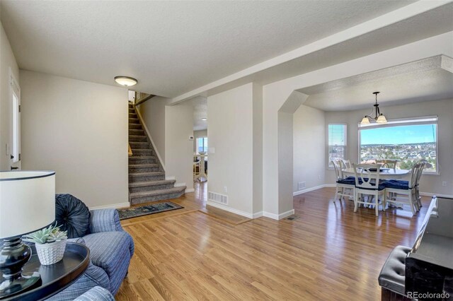 1944 Queens Canyon Ct, Colorado Springs, CO 80921 - living area with visible vents, baseboards, light wood-style floors, a textured ceiling, and stairs