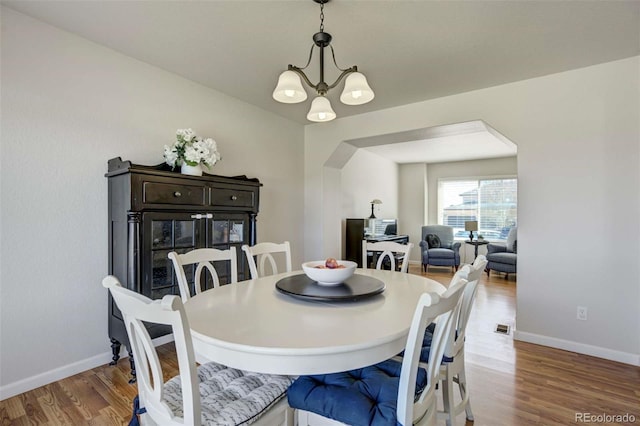 1944 Queens Canyon Ct, Colorado Springs, CO 80921 - dining space featuring arched walkways, baseboards, an inviting chandelier, and wood finished floors