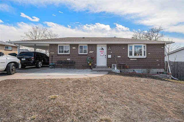 single story home with a carport, concrete driveway, fence, and brick siding