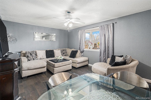 living area featuring a ceiling fan, a textured wall, dark wood-style flooring, and baseboards