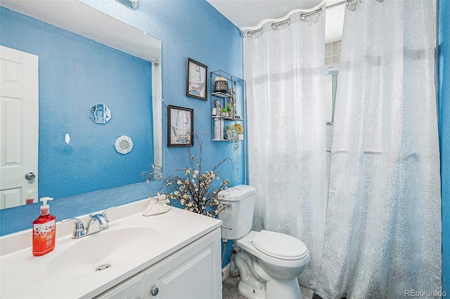 bathroom with toilet, vanity, and a textured wall