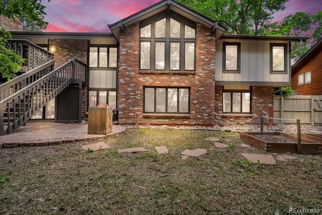 1665 W 113th Ave, Denver, CO 80234 - back of property at dusk with a vegetable garden, a patio area, brick siding, and stairs