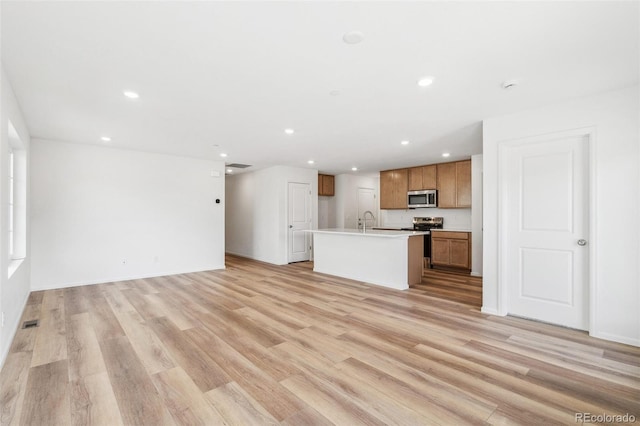 unfurnished living room featuring light wood-type flooring, a sink, visible vents, and recessed lighting