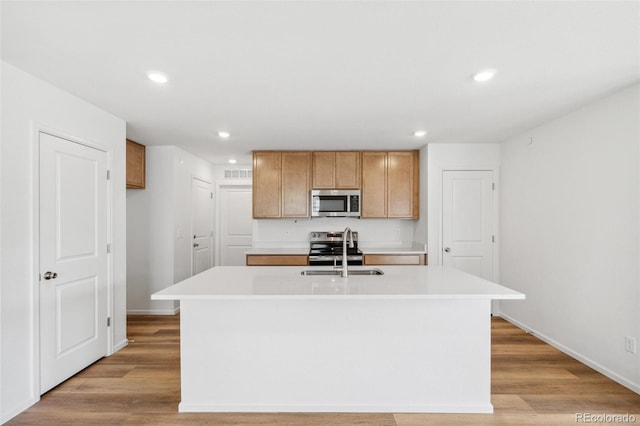 kitchen with stainless steel appliances, light countertops, a sink, and light wood-style flooring