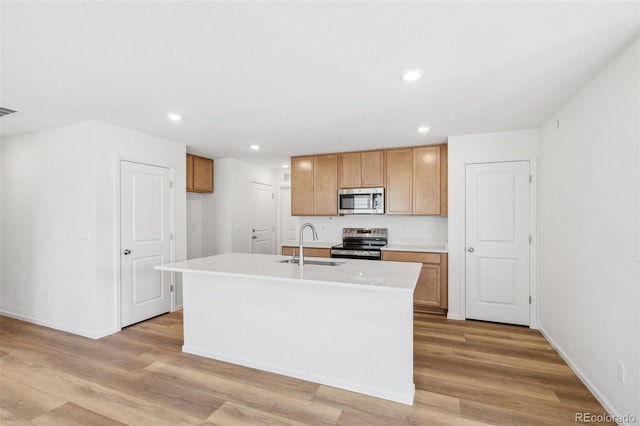 kitchen with stainless steel appliances, light wood-type flooring, a sink, and light countertops