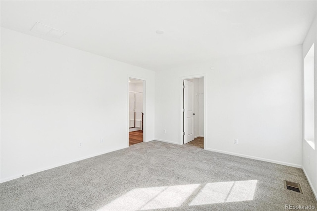 empty room with carpet floors, visible vents, and baseboards