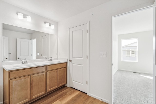 full bath with double vanity, wood finished floors, a sink, and visible vents