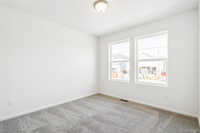 spare room with carpet flooring, visible vents, and baseboards