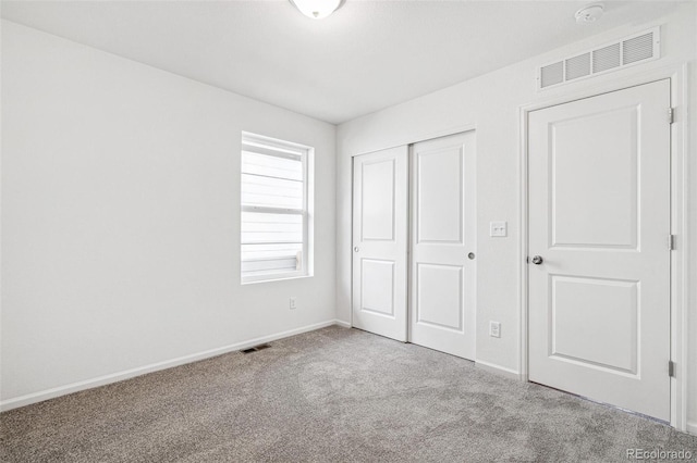 unfurnished bedroom with carpet floors, a closet, visible vents, and baseboards