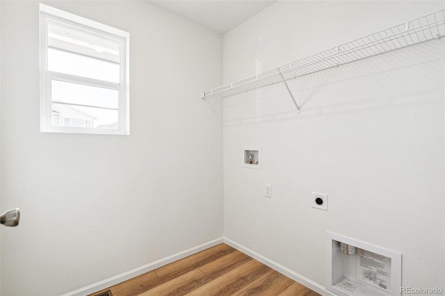 clothes washing area with hookup for a washing machine, light wood-style flooring, laundry area, baseboards, and electric dryer hookup