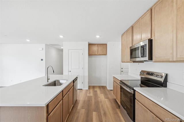 kitchen featuring recessed lighting, light countertops, light wood-style flooring, appliances with stainless steel finishes, and a sink