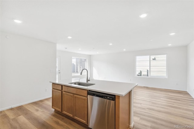 kitchen with a sink, light wood finished floors, a wealth of natural light, and dishwasher