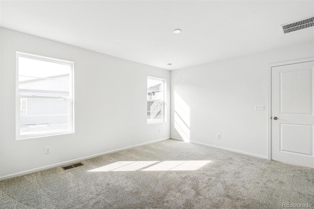 carpeted spare room featuring visible vents and baseboards