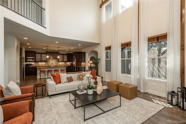 9266 E 35th Ave, Denver, CO 80238 - living area with arched walkways, dark wood-type flooring, baseboards, a towering ceiling, and recessed lighting
