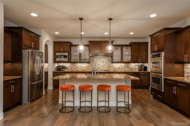 9266 E 35th Ave, Denver, CO 80238 - kitchen with appliances with stainless steel finishes, a sink, arched walkways, glass insert cabinets, and a breakfast bar area