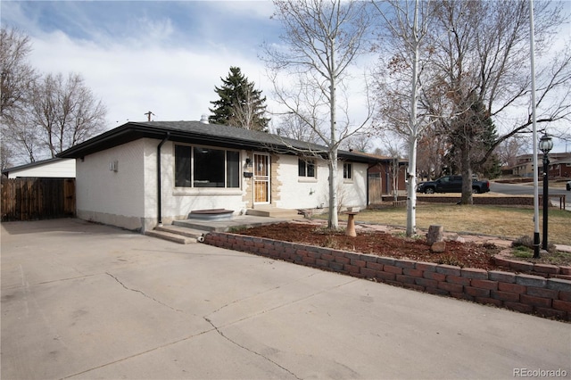 ranch-style home with brick siding, concrete driveway, and fence