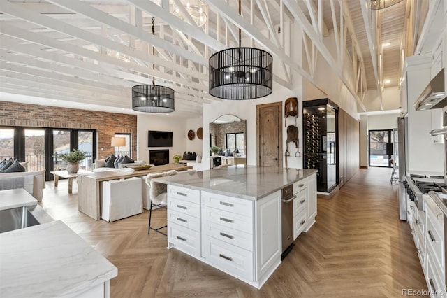 kitchen with light stone counters, a high ceiling, white cabinetry, open floor plan, and a center island