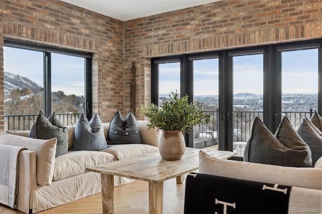 living room with a mountain view, brick wall, wood finished floors, and a wealth of natural light