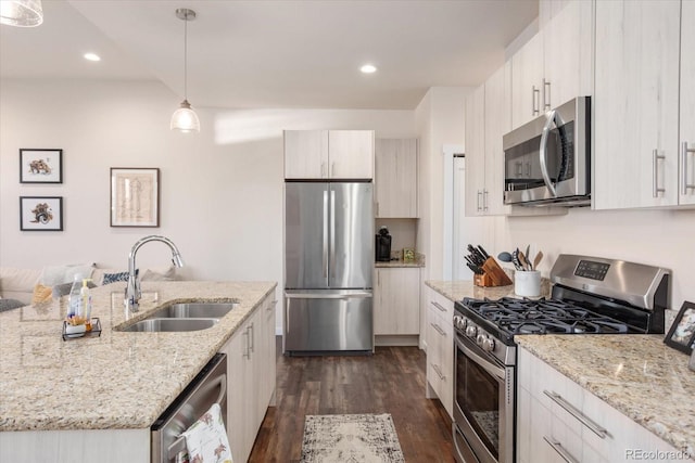 kitchen featuring light stone counters, appliances with stainless steel finishes, decorative light fixtures, and sink