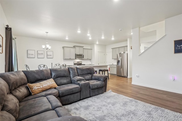 715 N Amory St, Watkins, CO 80137 - living area with light wood-style flooring, a chandelier, and baseboards