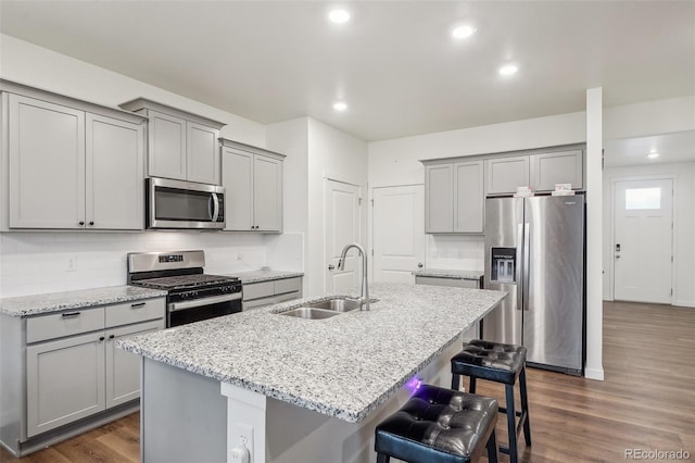 715 N Amory St, Watkins, CO 80137 - kitchen with appliances with stainless steel finishes, gray cabinets, a sink, a kitchen bar, and recessed lighting