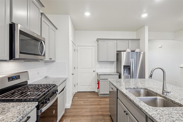 715 N Amory St, Watkins, CO 80137 - kitchen with appliances with stainless steel finishes, a sink, gray cabinets, backsplash, and wood finished floors