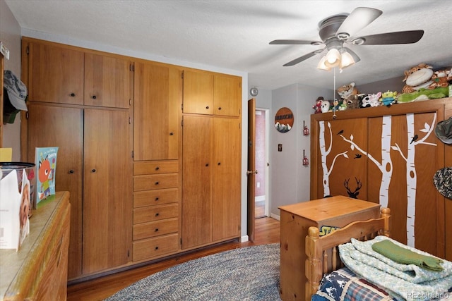 bedroom featuring ceiling fan, light hardwood / wood-style floors, and a textured ceiling