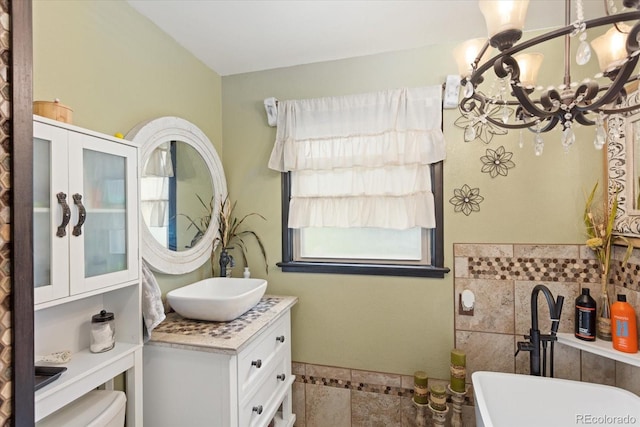 bathroom with tile patterned floors, vanity, a bathtub, and an inviting chandelier